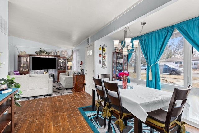 dining space with visible vents, vaulted ceiling, an inviting chandelier, and wood finished floors