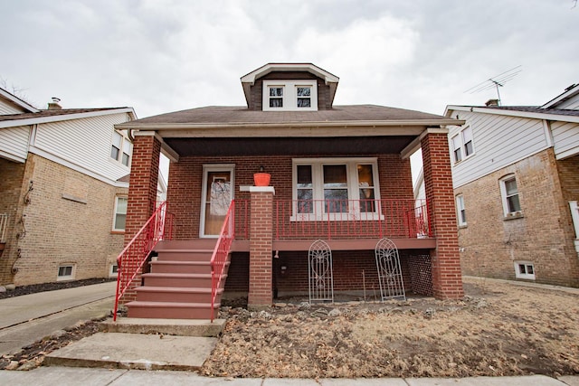 bungalow-style house with covered porch, brick siding, and stairs