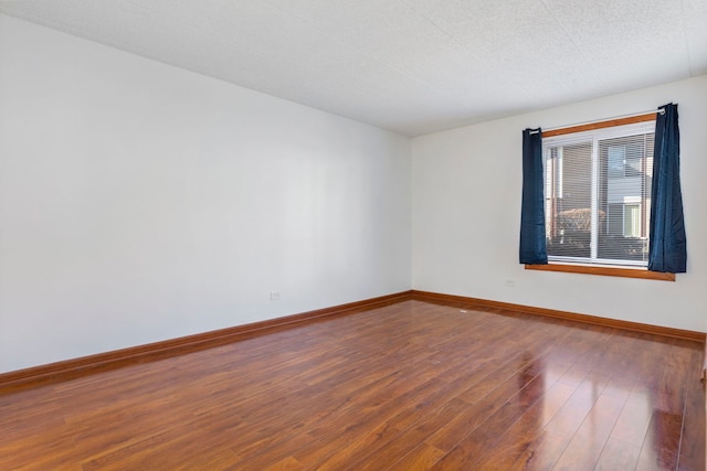 empty room featuring hardwood / wood-style flooring and baseboards