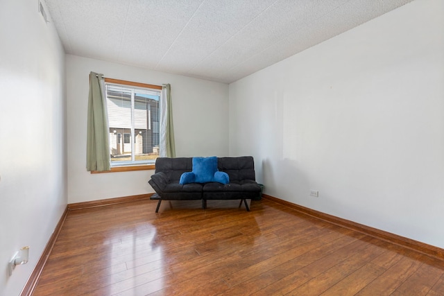 living area with a textured ceiling, baseboards, and hardwood / wood-style flooring