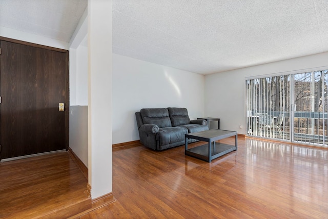 living area with a textured ceiling, baseboards, and wood finished floors