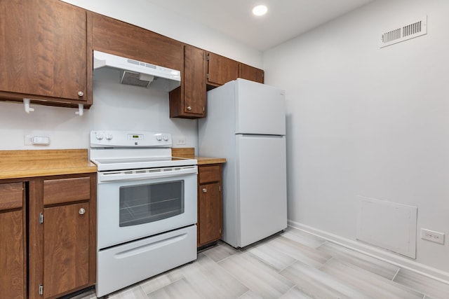 kitchen with visible vents, light countertops, white appliances, under cabinet range hood, and baseboards