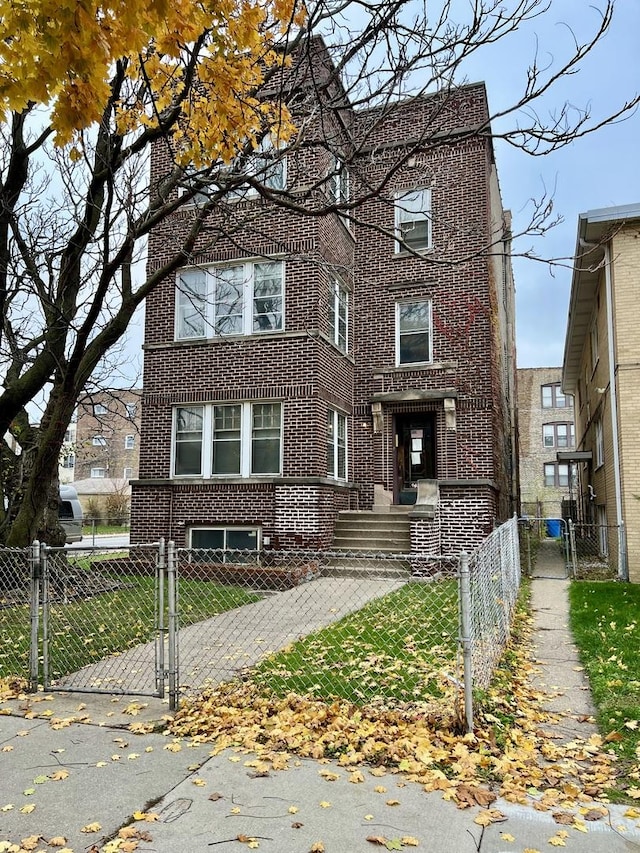 view of front of home with brick siding, a fenced front yard, and a gate