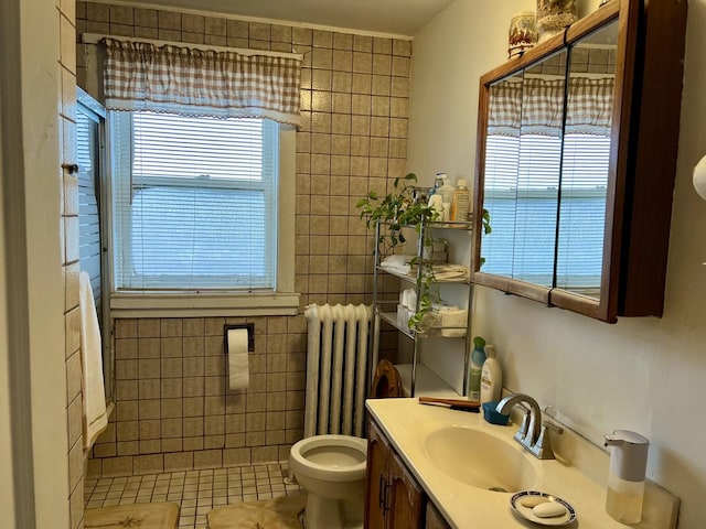 bathroom featuring radiator heating unit, plenty of natural light, vanity, and tile walls