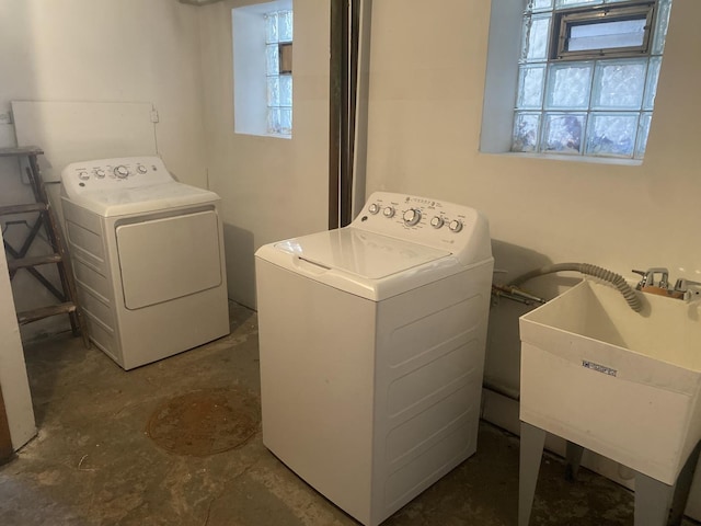 washroom featuring laundry area, plenty of natural light, washer and clothes dryer, and a sink