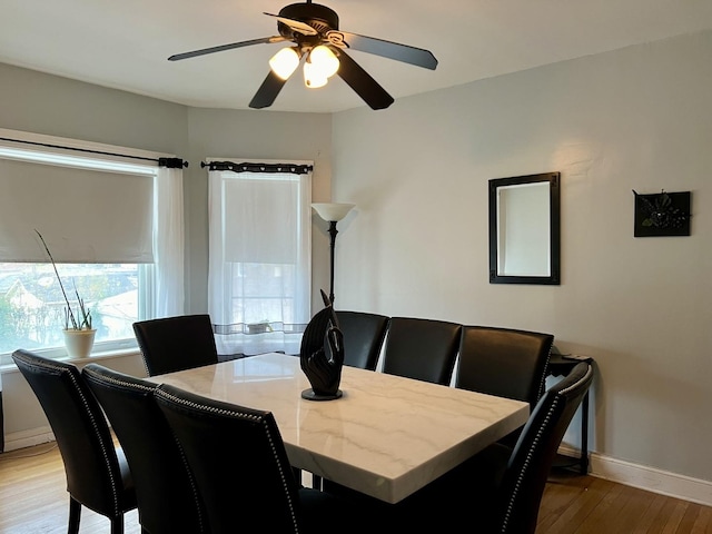 dining room featuring wood finished floors, a ceiling fan, and baseboards