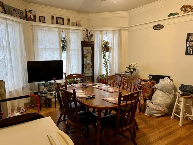 dining space with a wealth of natural light, crown molding, and wood finished floors