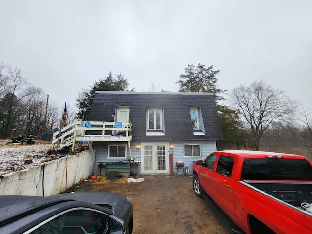 view of front facade featuring a shingled roof, french doors, and mansard roof