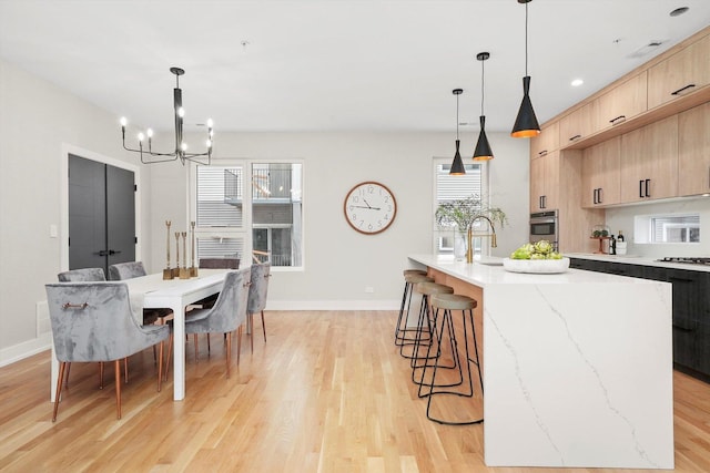 kitchen with light wood finished floors, light brown cabinetry, stainless steel appliances, an inviting chandelier, and modern cabinets