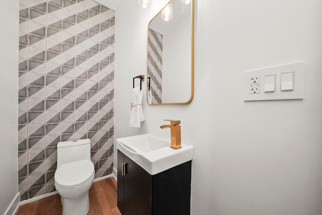 bathroom with vanity, toilet, wood finished floors, and baseboards