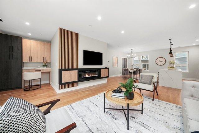 living area featuring a glass covered fireplace, recessed lighting, light wood-type flooring, and an inviting chandelier