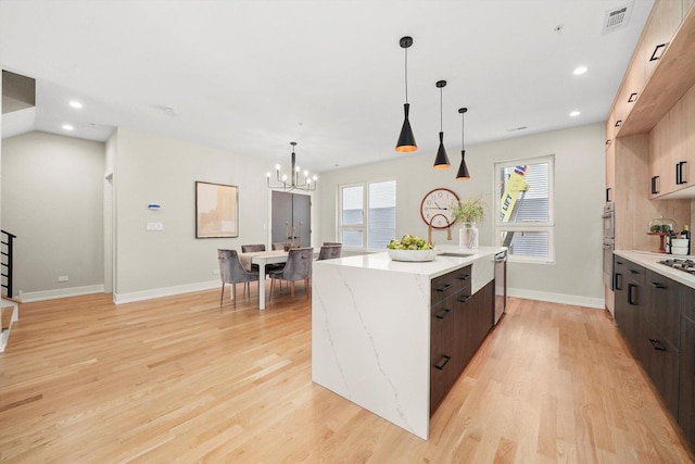 kitchen with an inviting chandelier, a center island with sink, modern cabinets, and visible vents