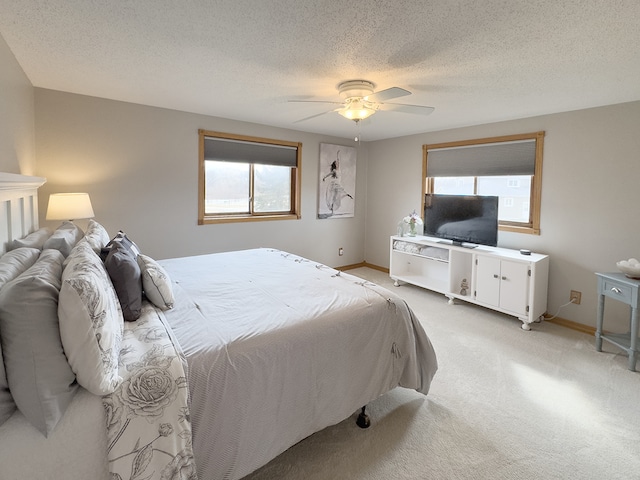 bedroom featuring light carpet, ceiling fan, a textured ceiling, and multiple windows