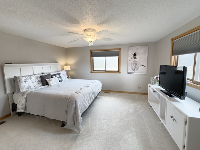 bedroom featuring light colored carpet, ceiling fan, baseboards, and multiple windows