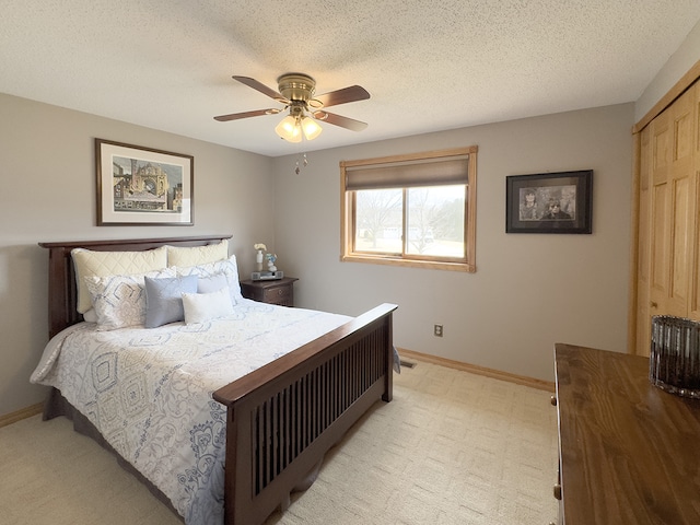 bedroom with a textured ceiling, a closet, a ceiling fan, and baseboards