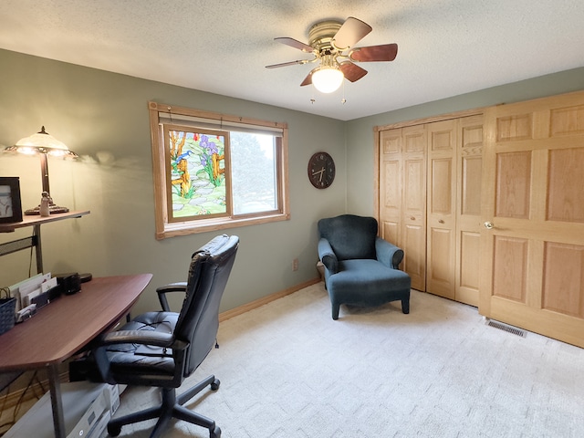 office featuring ceiling fan, a textured ceiling, light carpet, visible vents, and baseboards