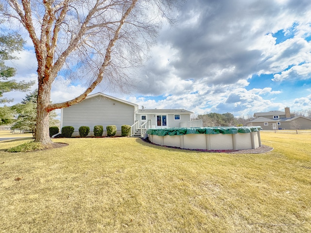 rear view of property with a covered pool and a yard