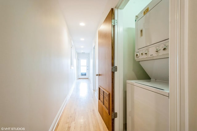 laundry area featuring stacked washer / drying machine, visible vents, light wood-type flooring, laundry area, and baseboards