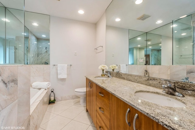 bathroom with tiled shower, a sink, toilet, and tile patterned floors