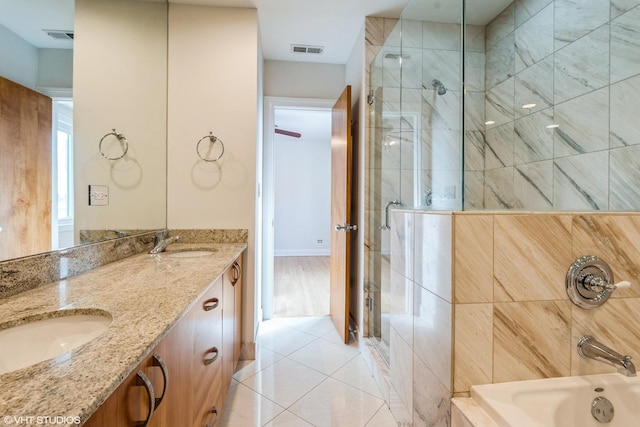 full bath with visible vents, a tile shower, and a sink