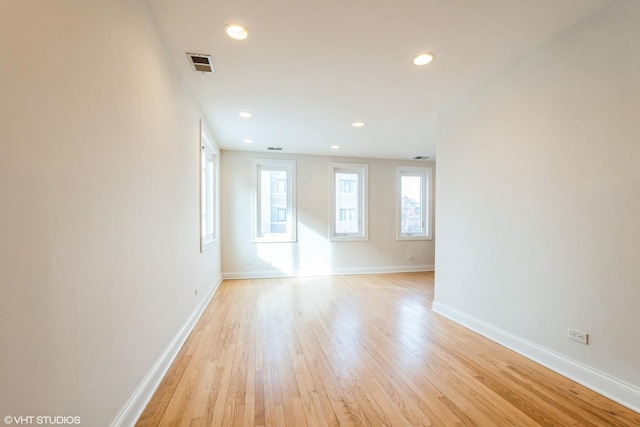 empty room with light wood-style floors, recessed lighting, visible vents, and baseboards