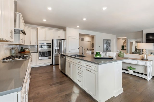 kitchen with stainless steel appliances, dark wood finished floors, a sink, and decorative backsplash