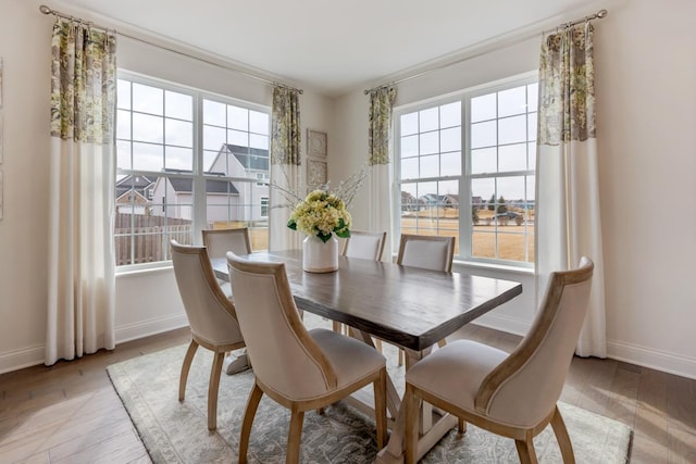 dining space with light wood finished floors, plenty of natural light, and baseboards