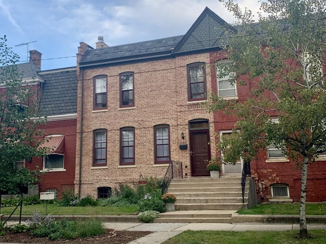 view of front facade with brick siding and a high end roof