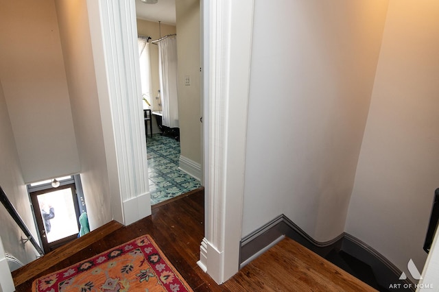 hallway with an upstairs landing, baseboards, and wood finished floors