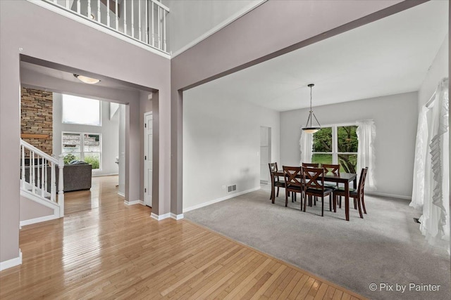 dining room with light wood-style flooring, stairway, plenty of natural light, and visible vents