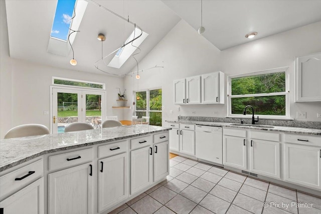 kitchen featuring a skylight, visible vents, white dishwasher, white cabinetry, and a sink