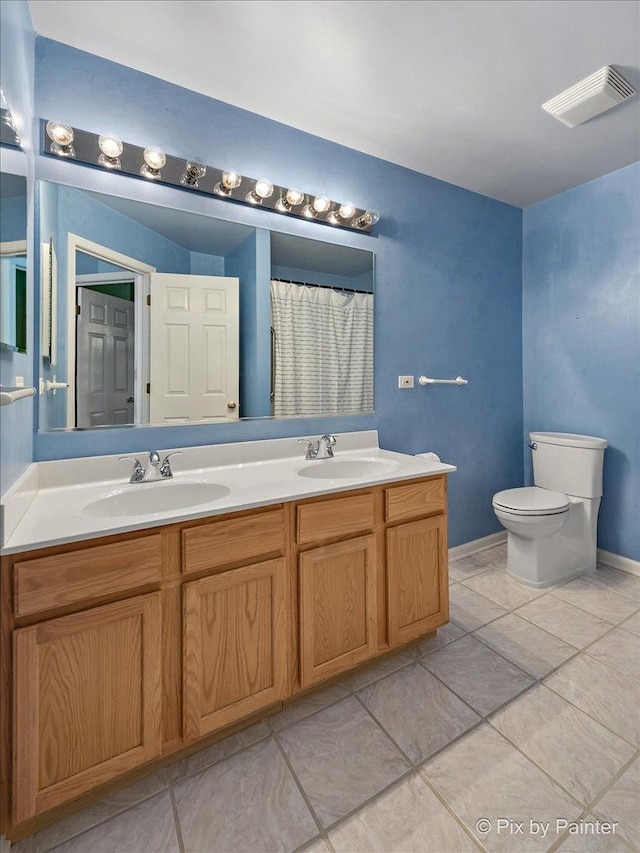 full bathroom with toilet, double vanity, a sink, and visible vents