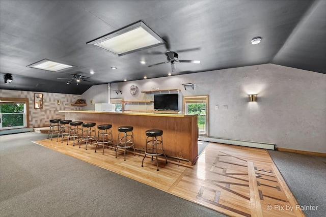 bar with a ceiling fan, a baseboard radiator, bar, and vaulted ceiling