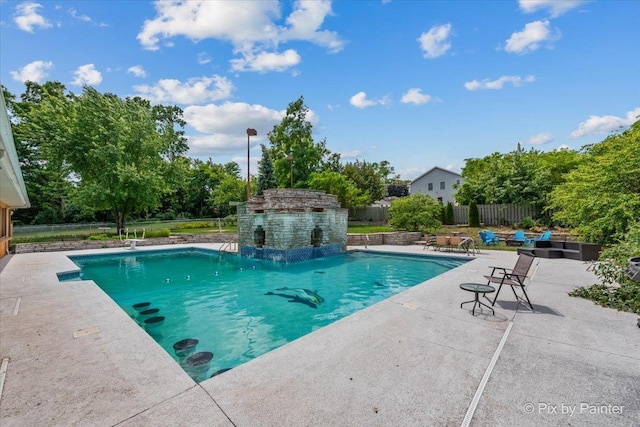 outdoor pool featuring a patio area, fence, and an outbuilding