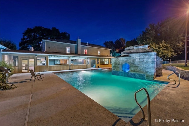 pool at twilight featuring a patio area and an outdoor pool