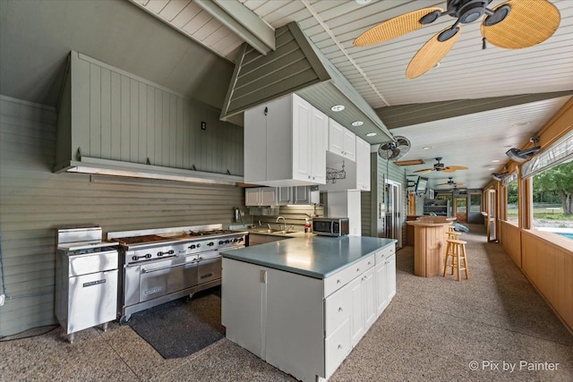 kitchen with white cabinets, dark countertops, lofted ceiling, wood walls, and a sink