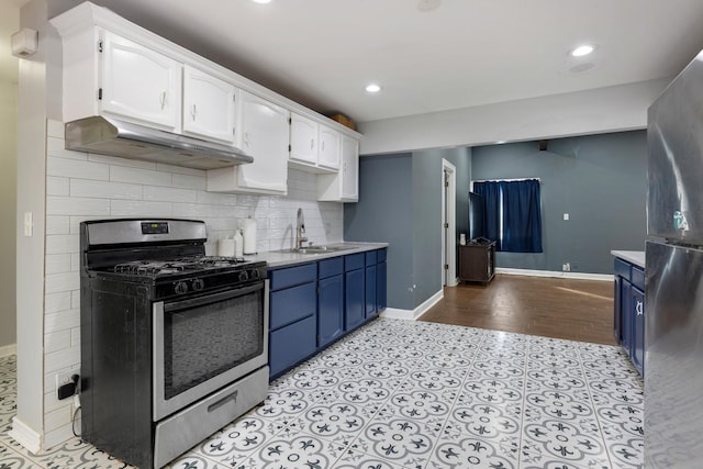 kitchen with stainless steel gas range oven, blue cabinets, under cabinet range hood, a sink, and white cabinetry