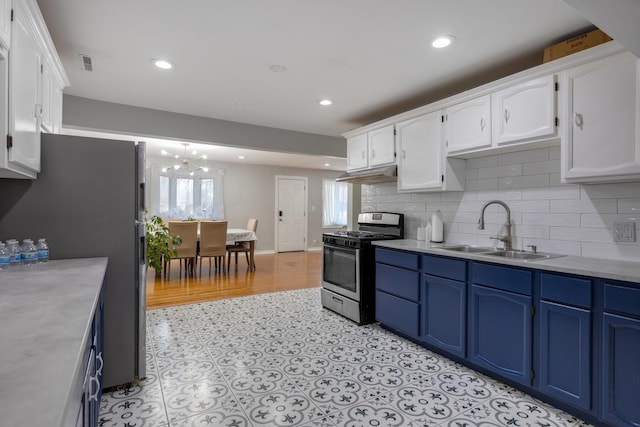 kitchen with appliances with stainless steel finishes, blue cabinets, a sink, and under cabinet range hood