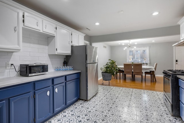 kitchen with stainless steel appliances, blue cabinetry, backsplash, and white cabinets