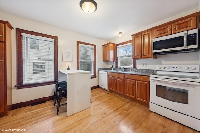 kitchen featuring white appliances, light wood-style flooring, baseboards, and brown cabinets