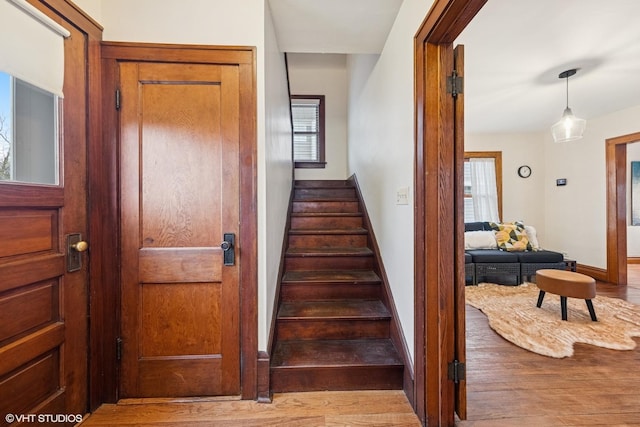 staircase with a wealth of natural light, baseboards, and wood finished floors