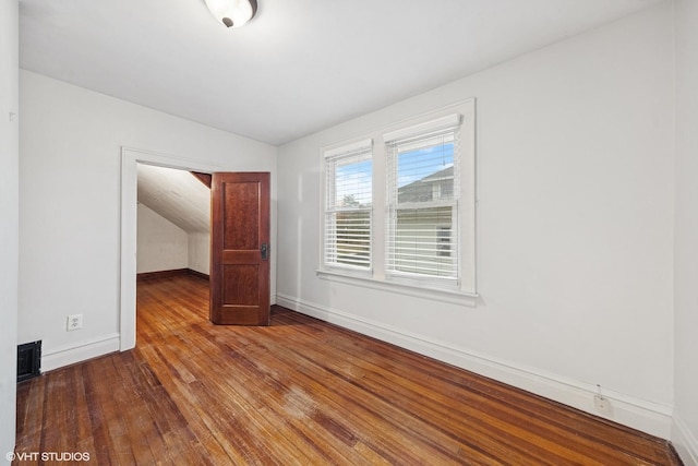 unfurnished bedroom with vaulted ceiling, hardwood / wood-style flooring, visible vents, and baseboards