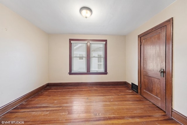 unfurnished room featuring visible vents, baseboards, and wood finished floors