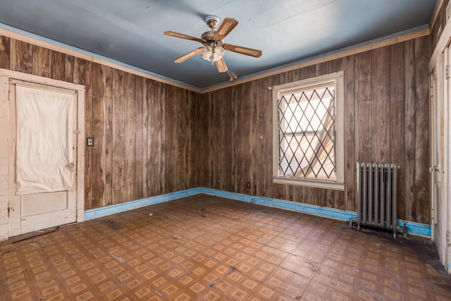 spare room with wood walls, radiator heating unit, a ceiling fan, and tile patterned floors