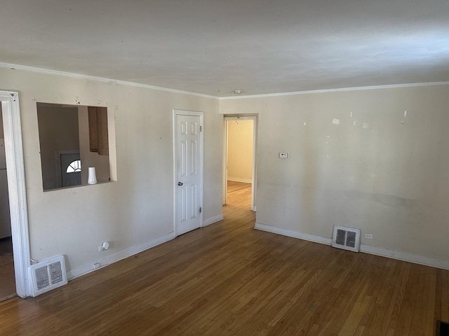 unfurnished room with ornamental molding, visible vents, baseboards, and wood finished floors