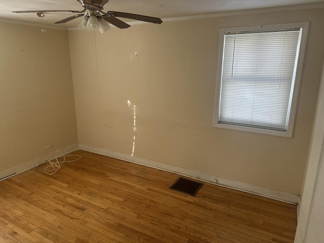 empty room with crown molding, visible vents, ceiling fan, light wood-type flooring, and baseboards