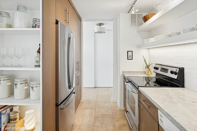kitchen with open shelves, stainless steel appliances, brown cabinets, light countertops, and track lighting