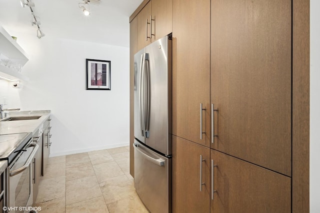 kitchen with appliances with stainless steel finishes, a sink, light countertops, and baseboards