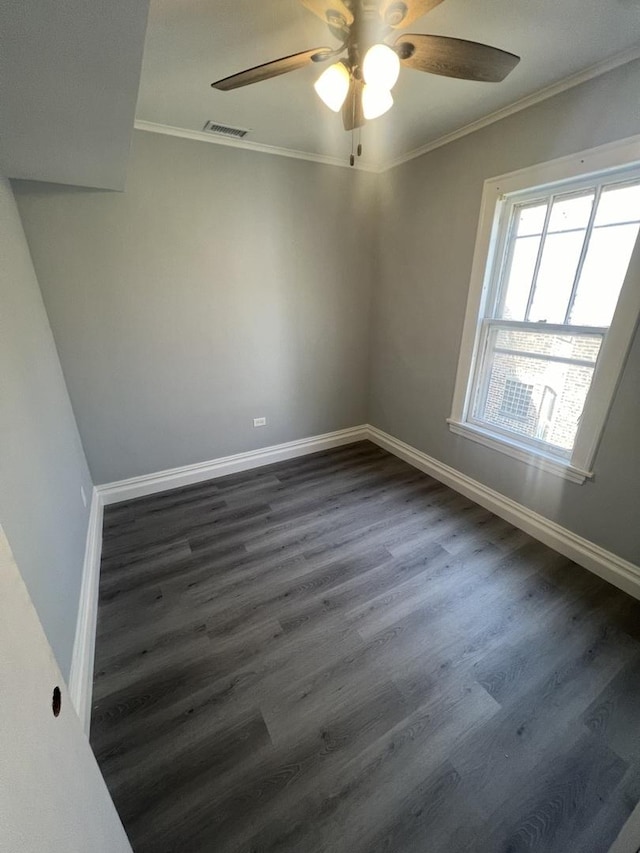 empty room with ornamental molding, dark wood-style flooring, visible vents, and baseboards