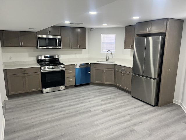 kitchen featuring visible vents, light countertops, light wood-style flooring, appliances with stainless steel finishes, and a sink